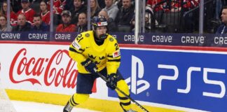 Viggo Björck, a top prospect for the Seattle Kraken in the 2026 NHL Draft, skating with the puck in his yellow Team Sweden number 21 jersey during an international game.