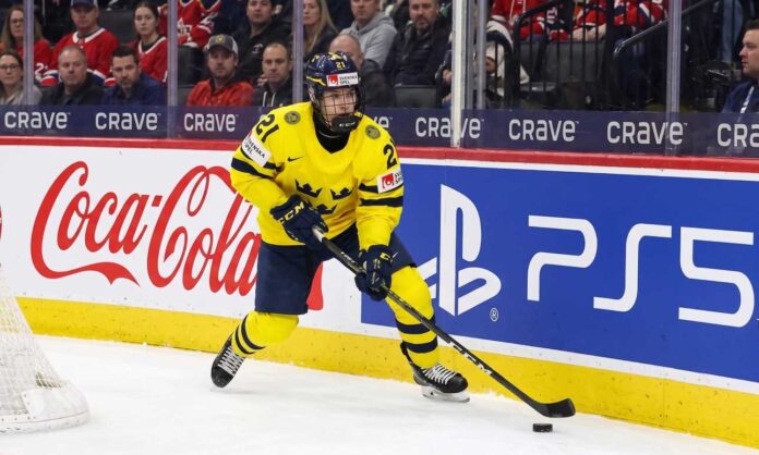 Viggo Björck, a top prospect for the Seattle Kraken in the 2026 NHL Draft, skating with the puck in his yellow Team Sweden number 21 jersey during an international game.