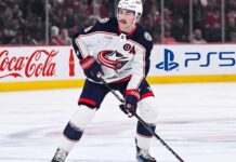 Zach Werenski Trade Rumors: Will the Columbus Blue Jackets Move Him? Zach Werenski, Columbus Blue Jackets star defenseman, during an NHL game, seen in his white away jersey. The photo captures him looking ahead, the primary focus of growing trade speculation for the team.
