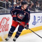 Will Zach Werenski Request a Trade From the Columbus Blue Jackets? Columbus Blue Jackets defenseman Zach Werenski skating in action during an NHL game, the subject of recent trade rumors regarding his future in Columbus.