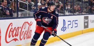 Will Zach Werenski Request a Trade From the Columbus Blue Jackets? Columbus Blue Jackets defenseman Zach Werenski skating in action during an NHL game, the subject of recent trade rumors regarding his future in Columbus.