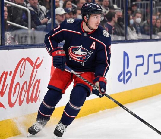 Will Zach Werenski Request a Trade From the Columbus Blue Jackets? Columbus Blue Jackets defenseman Zach Werenski skating in action during an NHL game, the subject of recent trade rumors regarding his future in Columbus.