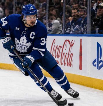 Auston Matthews Point Projections 2026-27: Can He Reach 95 Points? Auston Matthews skating in a Toronto Maple Leafs home jersey with the captain’s C during the 2026-27 NHL season.