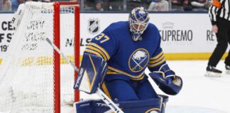 Connor Hellebuyck wearing a Buffalo Sabres home uniform and matching goalie equipment amid trade rumors involving the Winnipeg Jets.