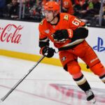 Does Cutter Gauthier Want Leo Carlsson’s $18 Million Contract From the Anaheim Ducks? Cutter Gauthier skating for the Anaheim Ducks beside Coca-Cola and PS5 rink-board ads amid NHL contract rumors