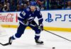 Jake Guentzel Fantasy Hockey Projection: How Many Points Will He Score in 2026-27? Jake Guentzel skating for the Tampa Bay Lightning during a 2026-27 Fantasy Hockey projection with Coca-Cola and PS5 ads on the boards.