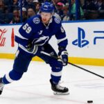 Jake Guentzel Fantasy Hockey Projection: How Many Points Will He Score in 2026-27? Jake Guentzel skating for the Tampa Bay Lightning during a 2026-27 Fantasy Hockey projection with Coca-Cola and PS5 ads on the boards.