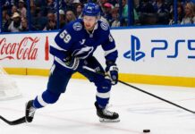 Jake Guentzel Fantasy Hockey Projection: How Many Points Will He Score in 2026-27? Jake Guentzel skating for the Tampa Bay Lightning during a 2026-27 Fantasy Hockey projection with Coca-Cola and PS5 ads on the boards.