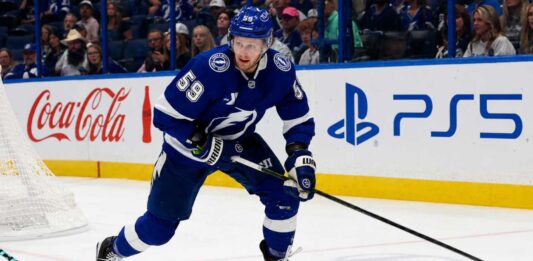Jake Guentzel Fantasy Hockey Projection: How Many Points Will He Score in 2026-27? Jake Guentzel skating for the Tampa Bay Lightning during a 2026-27 Fantasy Hockey projection with Coca-Cola and PS5 ads on the boards.