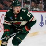 Kirill Kaprizov skating in a Minnesota Wild home jersey beside Coca-Cola and PS5 rink-board ads for a 2026-27 Fantasy Hockey projection