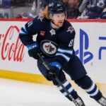Kyle Connor Fantasy Hockey Projection: Can the Winnipeg Jets Star Reach 100 Points? Kyle Connor skating in a Winnipeg Jets home jersey beside Coca-Cola and PS5 board ads for a 2026-27 Fantasy Hockey projection.