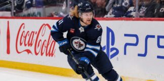Kyle Connor skating in a Winnipeg Jets home jersey beside Coca-Cola and PS5 board ads for a 2026-27 Fantasy Hockey projection.