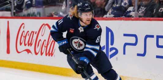 Kyle Connor skating in a Winnipeg Jets home jersey beside Coca-Cola and PS5 board ads for a 2026-27 Fantasy Hockey projection.