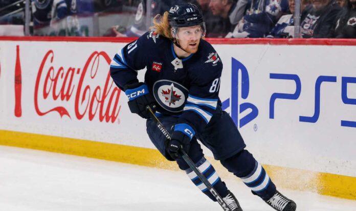 Kyle Connor skating in a Winnipeg Jets home jersey beside Coca-Cola and PS5 board ads for a 2026-27 Fantasy Hockey projection.