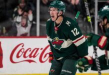 Matt Boldy celebrating in a Minnesota Wild jersey beside a Coca-Cola board ad for his 2026-27 fantasy hockey point projection.