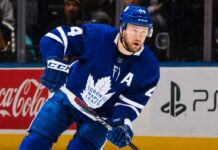 Morgan Rielly skating in a Toronto Maple Leafs home jersey as trade rumors suggest the veteran defenseman could remain in Toronto for the 2026-27 NHL season.