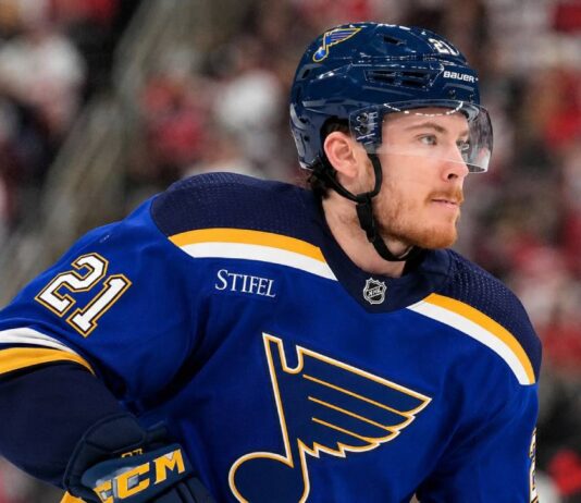 Alexander Nikishin wearing a St. Louis Blues home jersey amid NHL trade rumors involving the Carolina Hurricanes