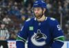 Shane Wright wearing a Vancouver Canucks home jersey amid trade rumors involving the Seattle Kraken, Zeev Buium and Tom Willander.