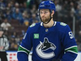 Shane Wright wearing a Vancouver Canucks home jersey amid trade rumors involving the Seattle Kraken, Zeev Buium and Tom Willander.