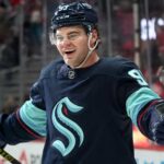 Concept image for Alex DeBrincat trade rumours showing a hockey player in a Seattle Kraken home jersey and helmet