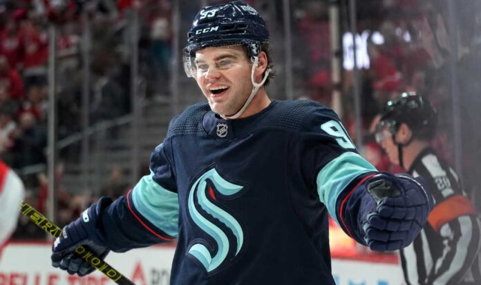 alex-debrincat-seattle-kraken-trade-rumors Concept image for Alex DeBrincat trade rumours showing a hockey player in a Seattle Kraken home jersey and helmet