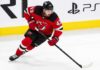 Quinn Hughes wearing a New Jersey Devils home jersey amid NHL trade rumors involving the Minnesota Wild and New Jersey Devils