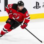 Quinn Hughes wearing a New Jersey Devils home jersey amid NHL trade rumors involving the Minnesota Wild and New Jersey Devils