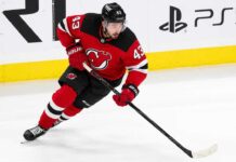 Quinn Hughes wearing a New Jersey Devils home jersey amid NHL trade rumors involving the Minnesota Wild and New Jersey Devils