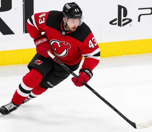 Quinn Hughes wearing a New Jersey Devils home jersey amid NHL trade rumors involving the Minnesota Wild and New Jersey Devils