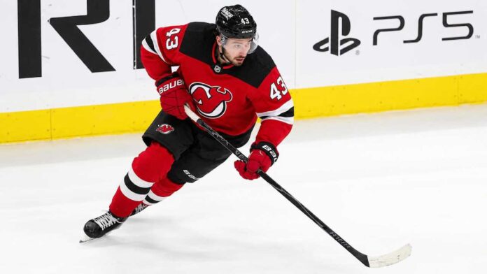Quinn Hughes wearing a New Jersey Devils home jersey amid NHL trade rumors involving the Minnesota Wild and New Jersey Devils
