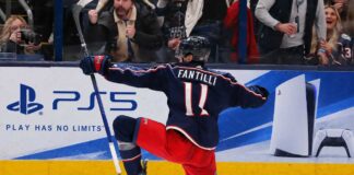Adam Fantilli Fantasy Hockey Projection 2026-27: Is a 72-Point Breakout Coming? Adam Fantilli of the Columbus Blue Jackets celebrates a goal in front of the crowd as a stylish PS5 rink board ad highlights his 2026-27 fantasy hockey breakout outlook.