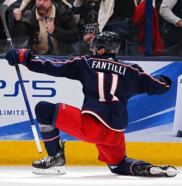 Adam Fantilli Fantasy Hockey Projection 2026-27: Is a 72-Point Breakout Coming? Adam Fantilli of the Columbus Blue Jackets celebrates a goal in front of the crowd as a stylish PS5 rink board ad highlights his 2026-27 fantasy hockey breakout outlook.