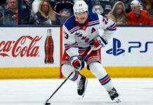 Adam Fox skating for the New York Rangers beside Coca-Cola and PS5 board ads in a 2026-27 fantasy hockey point projection.