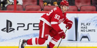 Alex DeBrincat Trade Rumors: Could Detroit’s Front-Office Chaos Put Another 40-Goal Star in Play? Detroit Red Wings forward in a home red jersey skating with the puck in a concept image for Alex DeBrincat trade rumors and Detroit Red Wings front-office uncertainty.