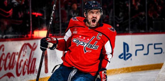 Alex Ovechkin Point Projections 2026-27: Washington Capitals Fantasy Outlook Alex Ovechkin celebrating for the Washington Capitals beside Coca-Cola and PS5 board ads in a 2026-27 fantasy hockey point projection.