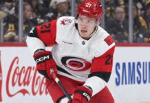 Alexander Nikishin Trade Rumors: Did His Hurricanes Camp Absence Just Force Carolina’s Hand? Alexander Nikishin of the Carolina Hurricanes skates with the puck during game action with Coca-Cola and Samsung ads on the boards in the background