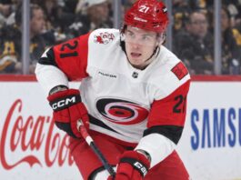 Alexander Nikishin of the Carolina Hurricanes skates with the puck during game action with Coca-Cola and Samsung ads on the boards in the background