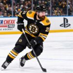Filip Hronek in a Boston Bruins home jersey skates during a concept image as Boston Bruins trade rumors link the Vancouver Canucks defenceman to Boston.