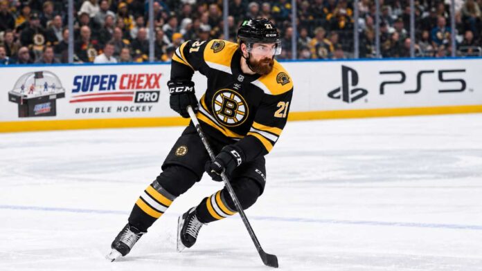 boston-bruins-filip-hronek-canucks-trade-rumors-2026 Filip Hronek in a Boston Bruins home jersey skates during a concept image as Boston Bruins trade rumors link the Vancouver Canucks defenceman to Boston.