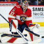 Florida Panthers goalie concept image tied to Connor Hellebuyck trade rumors, showing a goaltender in Florida Panthers gear in the crease with a Samsung TV ad on the boards.