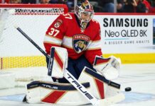 Connor Hellebuyck Trade Rumors: Did Friedman Just Reveal Florida’s Failed Blockbuster Offer? Florida Panthers goalie concept image tied to Connor Hellebuyck trade rumors, showing a goaltender in Florida Panthers gear in the crease with a Samsung TV ad on the boards.