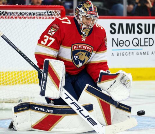 Florida Panthers goalie concept image tied to Connor Hellebuyck trade rumors, showing a goaltender in Florida Panthers gear in the crease with a Samsung TV ad on the boards.