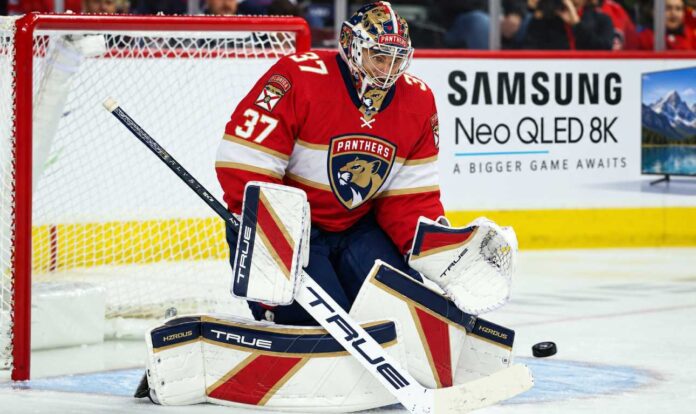 connor-hellebuyck-florida-panthers-winnipeg-jets-trade-rumors Florida Panthers goalie concept image tied to Connor Hellebuyck trade rumors, showing a goaltender in Florida Panthers gear in the crease with a Samsung TV ad on the boards.
