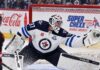 Connor Hellebuyck makes a glove save for the Winnipeg Jets as NHL trade rumors intensify ahead of training camp.