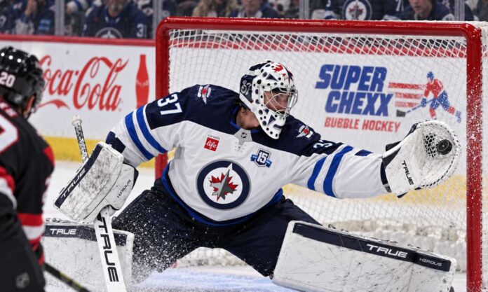 connor-hellebuyck-jets-trade-rumors-training-camp Connor Hellebuyck makes a glove save for the Winnipeg Jets as NHL trade rumors intensify ahead of training camp.
