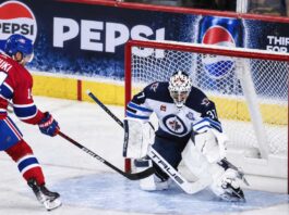 Nick Suzuki of the Montreal Canadiens attacks the net against Winnipeg Jets goalie Connor Hellebuyck amid NHL trade rumors linking Hellebuyck to Montreal.