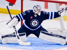 Connor Hellebuyck of the Winnipeg Jets makes a save amid trade rumors involving the Carolina Hurricanes and St. Louis Blues.
