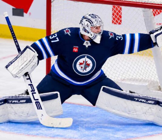 Connor Hellebuyck of the Winnipeg Jets makes a save amid trade rumors involving the Carolina Hurricanes and St. Louis Blues.