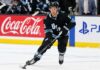 Dylan Guenther Point Projections 2026-27: Utah Mammoth Fantasy Outlook Dylan Guenther skating for the Utah Mammoth beside Coca-Cola and PS5 board ads in a 2026-27 fantasy hockey point projection.