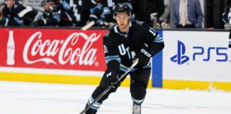 Dylan Guenther skating for the Utah Mammoth beside Coca-Cola and PS5 board ads in a 2026-27 fantasy hockey point projection.
